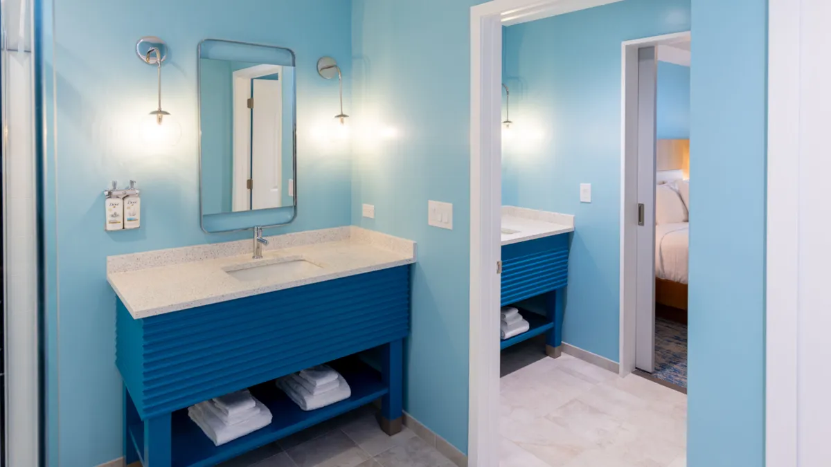 A bright, inviting bathroom with a striking blue vanity, a large mirror, and contemporary lighting fixtures. The space looks fresh, well-appointed, and designed for both comfort and style, echoing the concept of upgraded bathrooms.