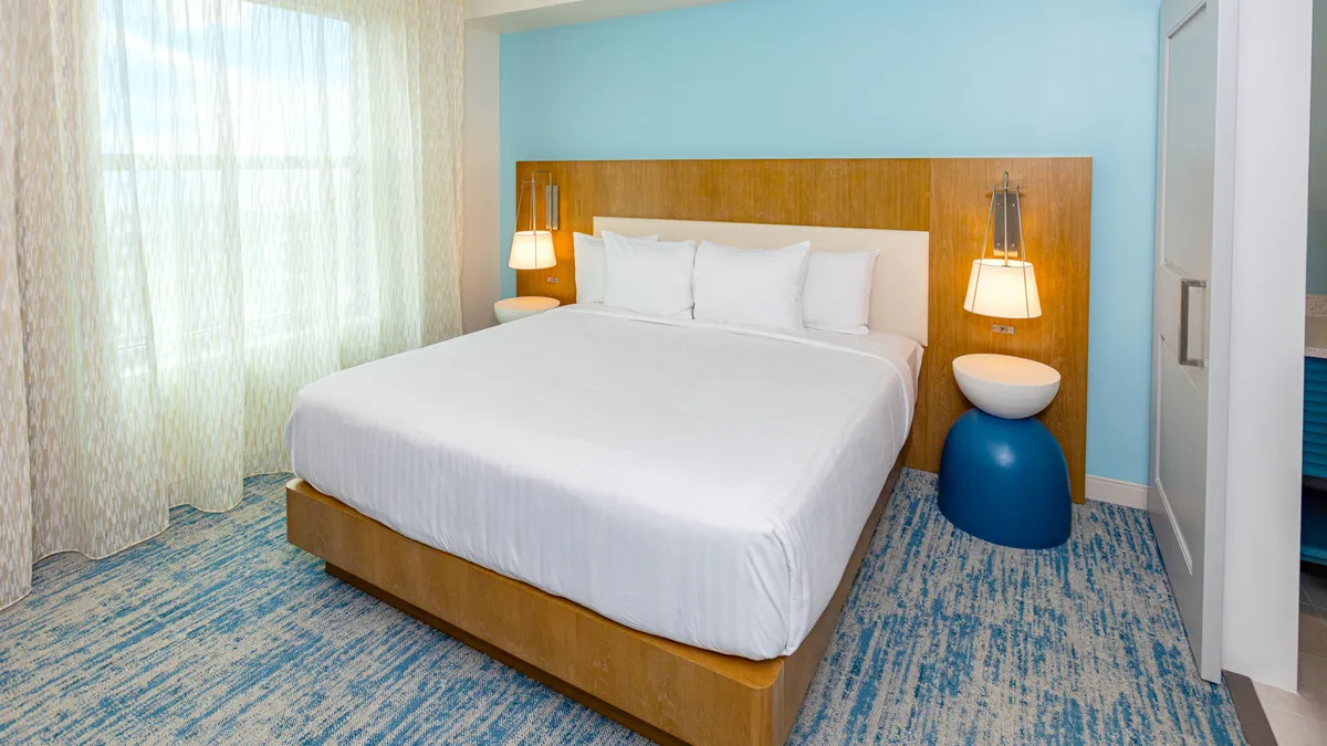 A cozy, sun-drenched bedroom with a comfortable bed, elegant headboard, matching nightstands, and soft curtains filtering the morning light. The inviting atmosphere suggests moments of relaxation, rest, and the enjoyment of peaceful mornings.